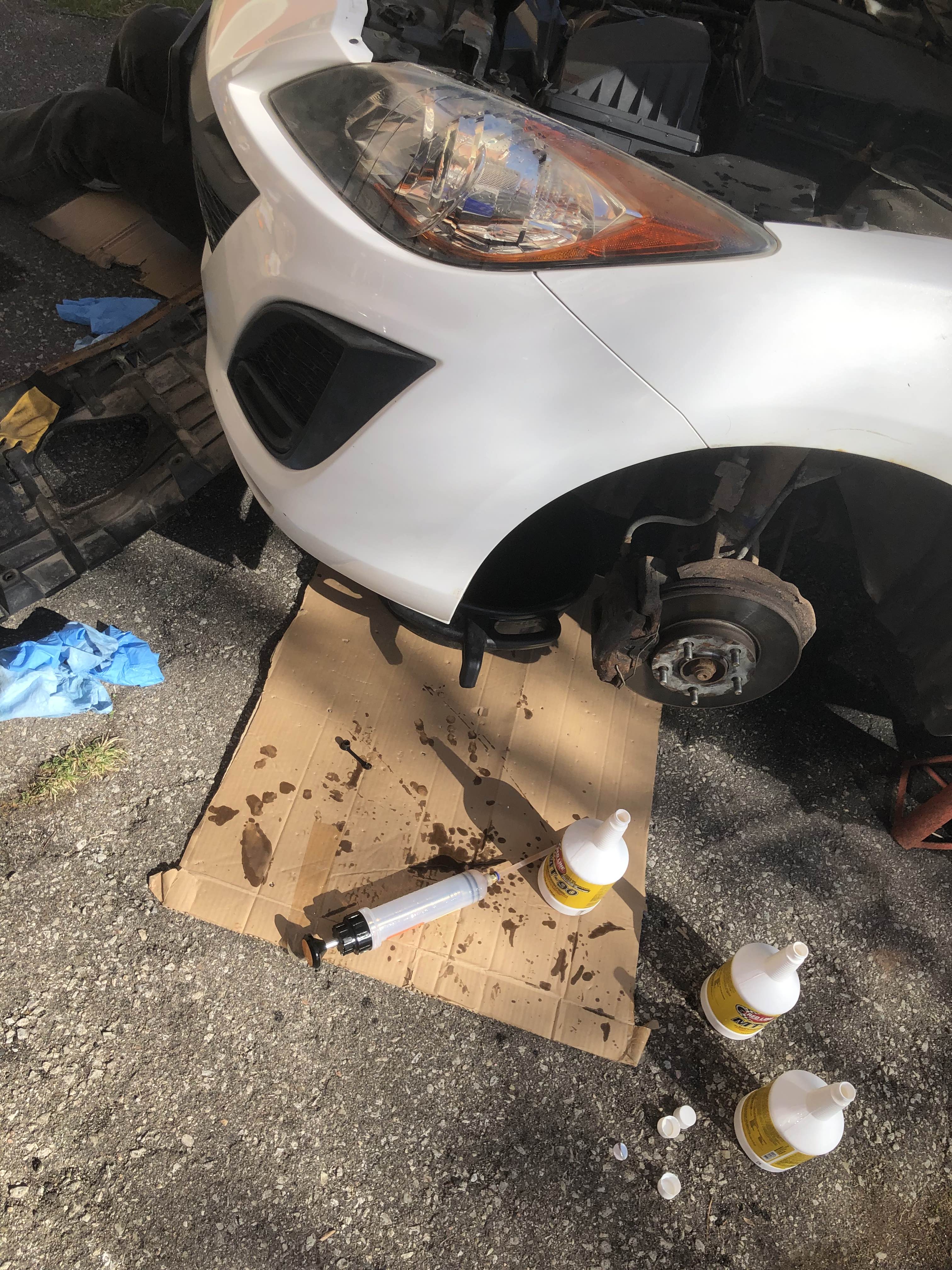 Empty gear oil bottles next to car